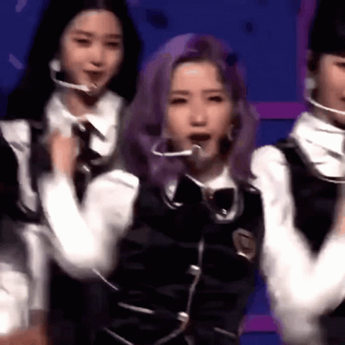 A Group Of Young Women Are Standing Next To Each Other On A Stage . One Of The Girls Has Purple Hair . GIF