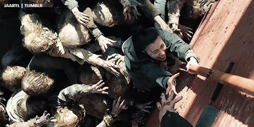 A Group Of Zombies Are Reaching For A Man 'S Hand In A Scene From A Movie GIF