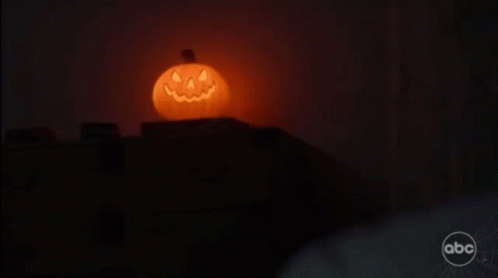a halloween pumpkin with a face carved into it is lit up in the dark .