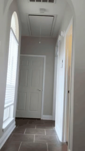 A Hallway In A House With A Ceiling Fan Above The Door GIF