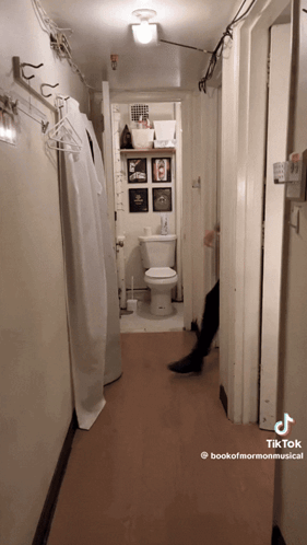 A Hallway With A Toilet And A Sign That Says Bookofmormonmusical GIF
