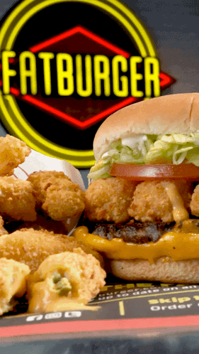 A Hamburger And Fried Shrimp Are On A Plate In Front Of A Sign That Says Fatburger GIF