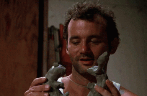 A Hand Holds A Piece Of Clay In Front Of A Pile Of Granite GIF