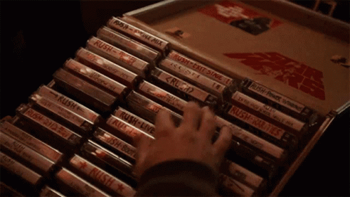 A Hand Is Holding A Cassette Tape That Says Rush On It GIF