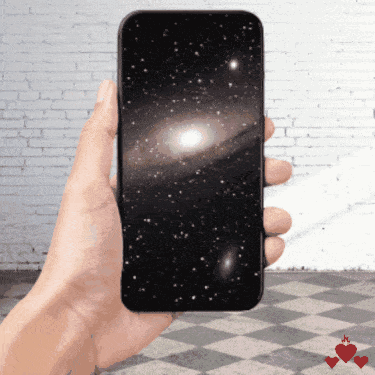 A Hand Is Holding A Cell Phone With A Picture Of The Galaxy On The Screen GIF