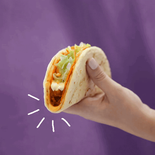 A Hand Is Holding A Taco With Lettuce And Cheese GIF