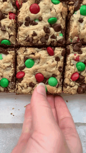 A Hand Is Reaching For A Cookie Bar With M & M 'S GIF