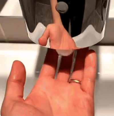 a hand with a ring is being washed in a bathroom sink