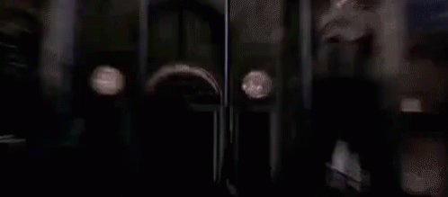 A Haunted Mansion Sign Is Behind A Fence In The Rain . GIF