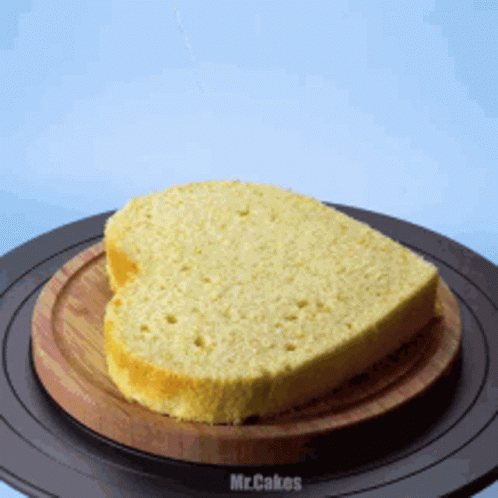 A Heart Shaped Loaf Of Bread Is On A Wooden Cutting Board GIF
