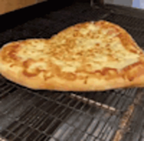 A Heart Shaped Pizza Is Sitting On A Wire Rack On A Grill . GIF