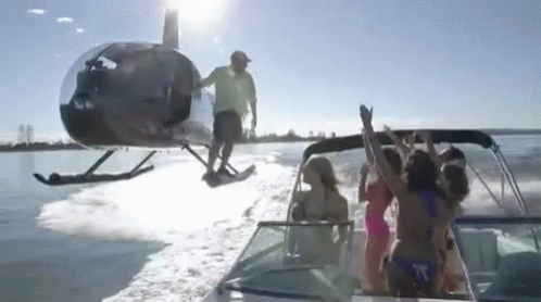 A Helicopter Is Flying Over A Boat Full Of People GIF