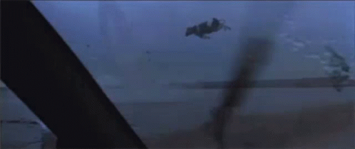 A Helicopter Is Flying Over A Body Of Water In The Dark GIF