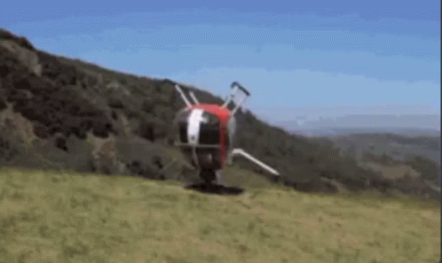 A Helicopter Is Flying Over A Grassy Hillside With Trees In The Background GIF