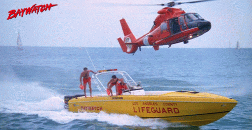 A Helicopter Is Flying Over A Yellow Lifeguard Boat GIF