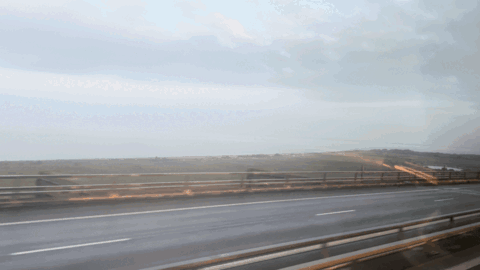 A Highway With A Bridge In The Background And A Cloudy Sky GIF