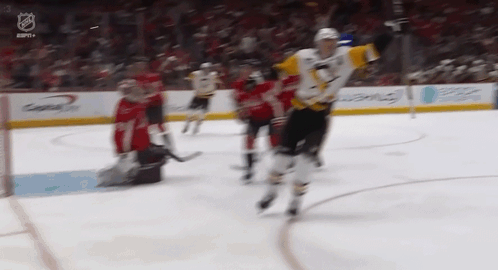 A Hockey Game Is Being Played In A Stadium With A Goalie In The Background . GIF
