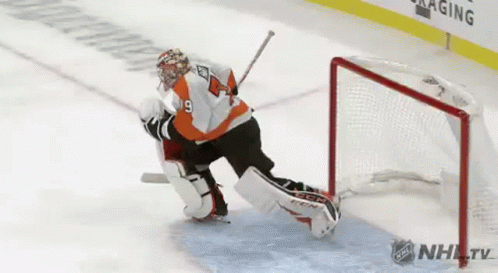 A Hockey Goalie Is Making A Save On A Goal During A Game . GIF