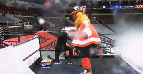 A Hockey Player In An Orange And White Uniform Stands On A Staircase GIF
