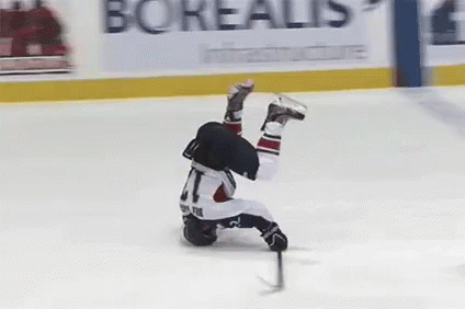 A Hockey Player Is Falling On His Back On The Ice While Holding A Puck . GIF