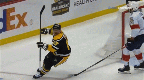A Hockey Player Is Holding A Puck In Front Of A Fedex Sign GIF