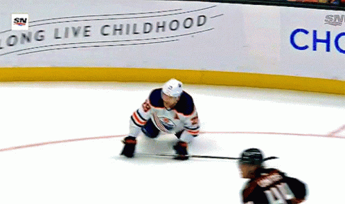 A Hockey Player Is Kneeling On The Ice In Front Of A Sign That Says Long Live Childhood GIF