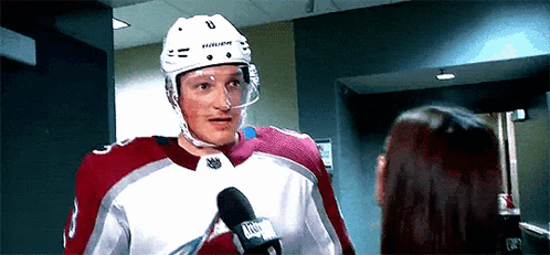 a hockey player is talking into a microphone while standing next to a woman .