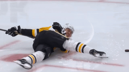 A Hockey Player Laying On The Ice With A Stick GIF