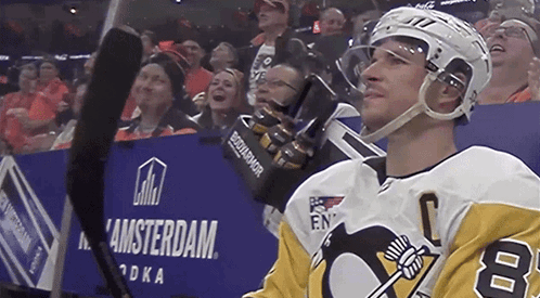 A Hockey Player Stands In Front Of A Sign That Says Amsterdam GIF