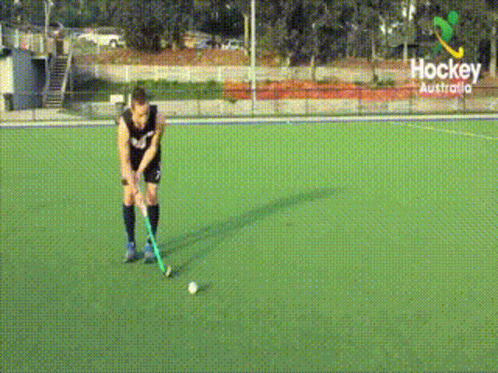 A Hockey Player Stands On A Field With A Sign That Says Hockey Australia GIF