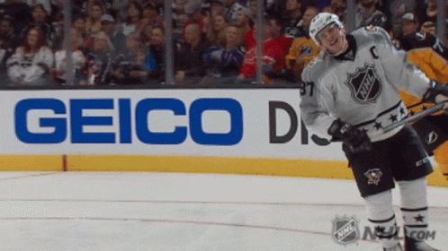 A Hockey Player Stands On The Ice In Front Of A Sign For Geico GIF