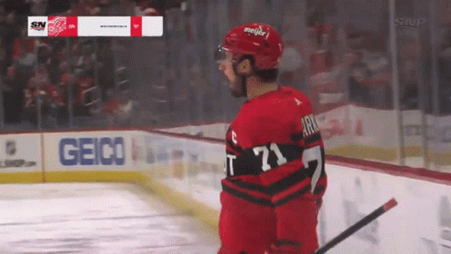 A Hockey Player Stands On The Ice With A Geico Sign In The Background GIF
