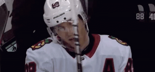 A Hockey Player Wearing A Bauer Helmet Is Holding A Hockey Stick GIF