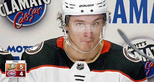 A Hockey Player Wearing A Bauer Helmet Stands In Front Of A Scoreboard GIF