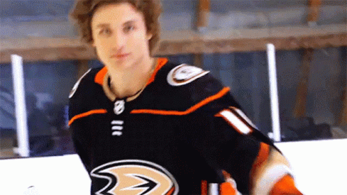 A Hockey Player Wearing A Black And Orange Jersey With A Ducks Logo On It GIF