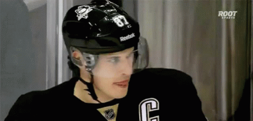 A Hockey Player Wearing A Black Helmet And A Black Jersey With The Number 87 On It . GIF