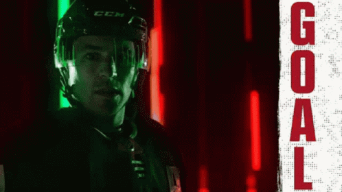 A Hockey Player Wearing A Ccm Helmet Stands In Front Of A Neon Sign That Says Goal GIF