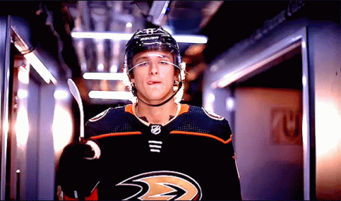 A Hockey Player Wearing A Helmet And A Jersey That Says Ducks Sticking Out His Tongue GIF