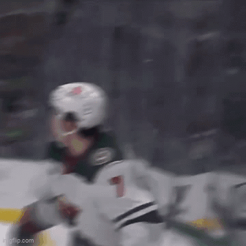 A Hockey Player Wearing A Helmet Is Flying Through The Air While Playing Ice Hockey . GIF