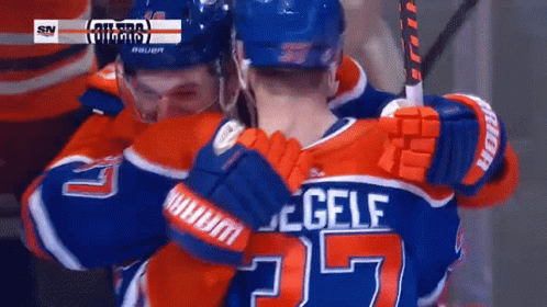 A Hockey Player Wearing A Number 25 Jersey Is Hugging Another Player GIF
