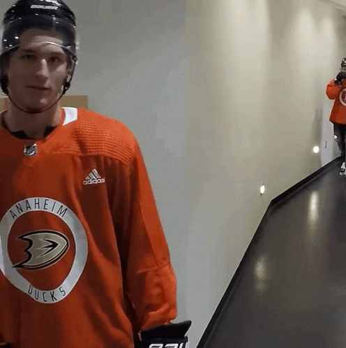 A Hockey Player Wearing An Anaheim Ducks Jersey Stands In A Hallway GIF