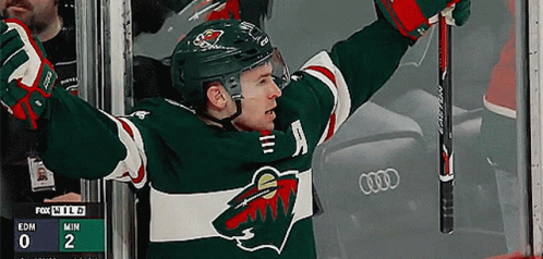 A Hockey Player With His Arms In The Air And A Scoreboard Behind Him That Says Fox Wild GIF