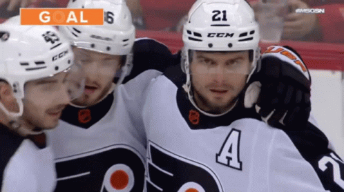 A Hockey Player With The Number 21 On His Helmet Is Surrounded By His Teammates GIF