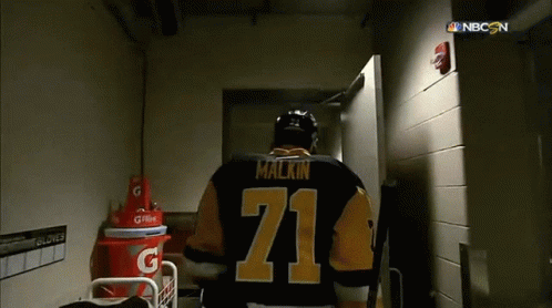 A Hockey Player With The Number 71 On His Jersey Walks Through A Doorway GIF