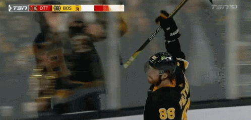 A Hockey Player With The Number 88 On His Jersey Holds His Stick In The Air GIF