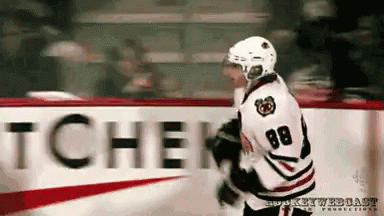 A Hockey Player With The Number 88 On His Jersey Stands In Front Of A Sign That Says Tchen GIF