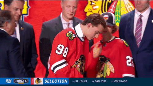 A Hockey Player With The Number 98 On His Jersey Stands Next To Another Player GIF