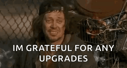 A Homeless Man Is Smiling And Saying `` Im Grateful For Any Upgrades '' While Sitting Next To A Trash Can . GIF