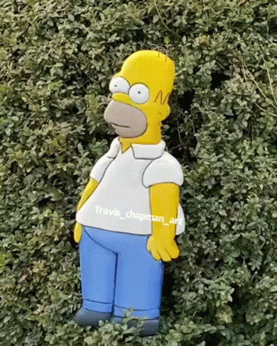 A Homer Simpson Statue Is Standing In A Bush GIF