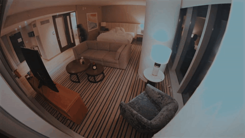 A Hotel Room With A Couch A Chair And A Tv GIF